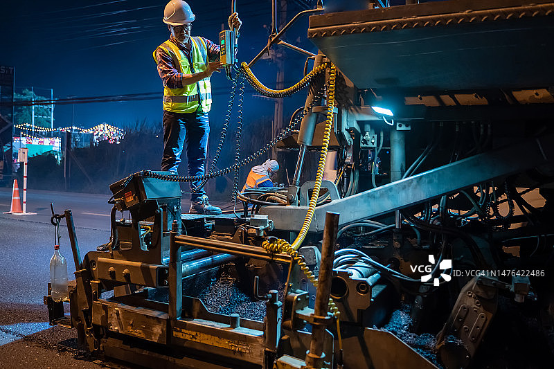 夜晚加班的工程师正在监督施工并用沥青修复路面图片素材