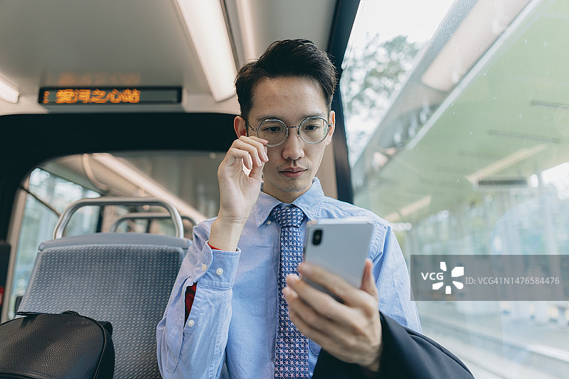 一名亚洲男子在上班途中使用手机图片素材