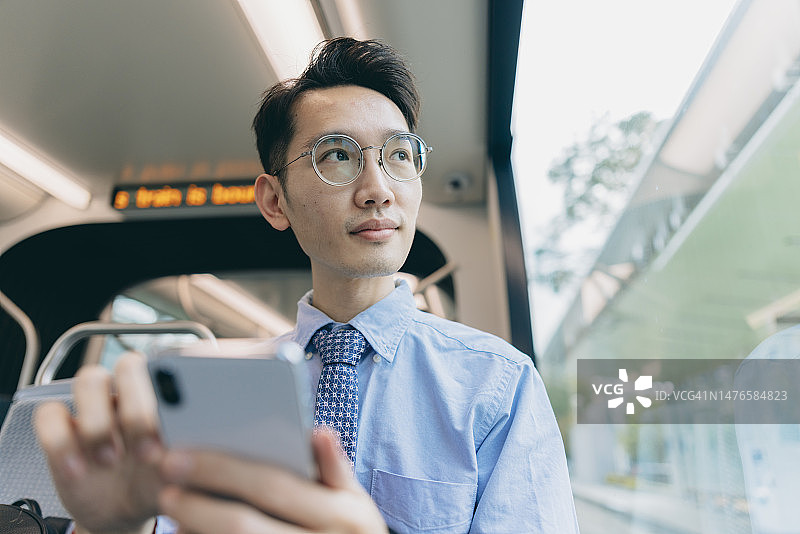 一名亚洲男子在上班途中使用手机图片素材