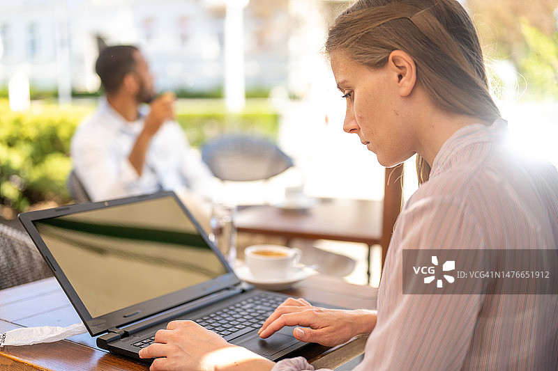 企业家在户外咖啡馆使用笔记本电脑工作图片素材