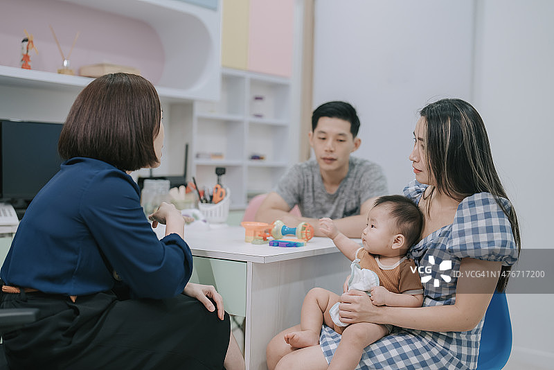 华人女儿科医生向忧心忡忡的婴儿父母解释病情图片素材