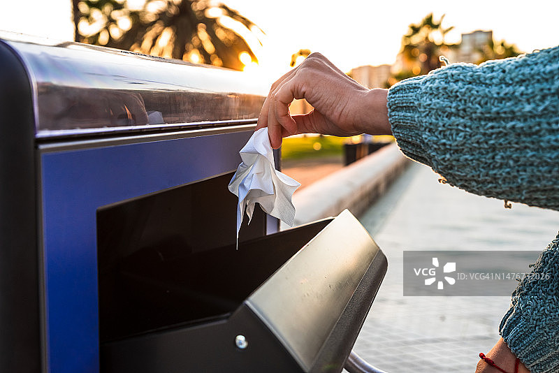 女人将纸巾扔进垃圾桶，循环利用与气候变化概念图片素材