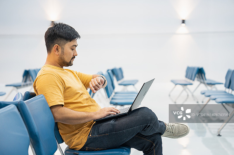 在机场大厅里，一位商人正在使用笔记本电脑和智能手机图片素材