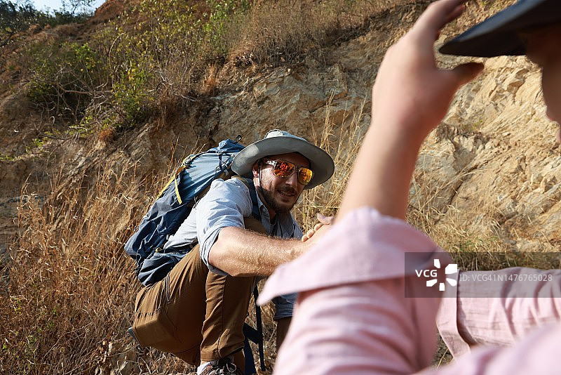 登山队手牵手互相帮助攀登山岩，冒险旅行概念图片素材