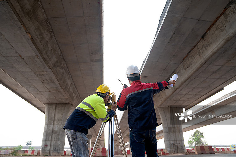 团队合作：测量工程师使用经纬仪进行道路测量图片素材