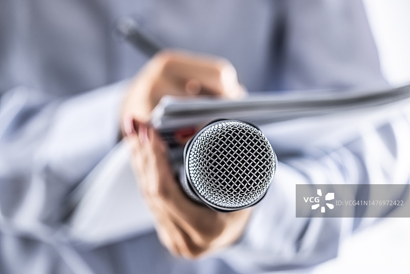 记者在新闻发布会上拿着麦克风并在笔记本上记录信息图片素材