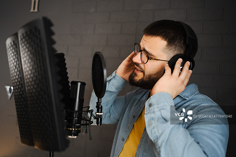 男人在录音棚戴着耳机用麦克风唱歌图片素材