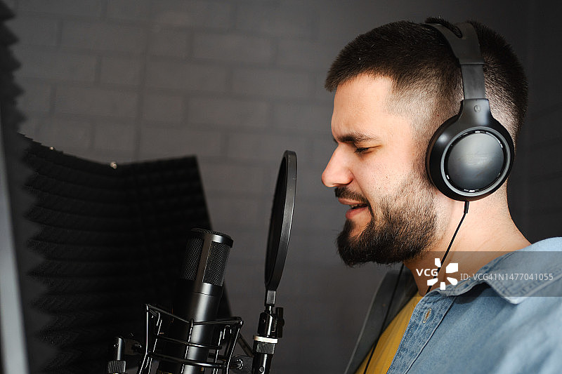 男人在录音棚戴着耳机用麦克风唱歌图片素材