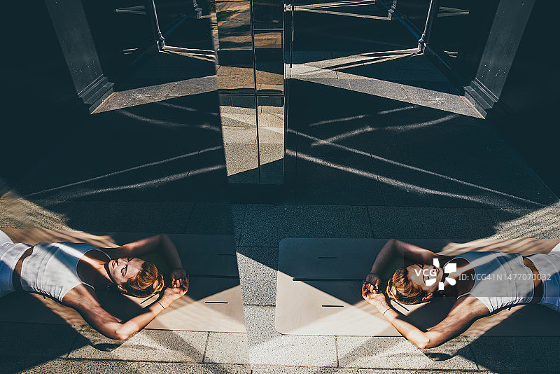 身穿白色运动服的苗条女子在地板上练习瑜伽图片素材