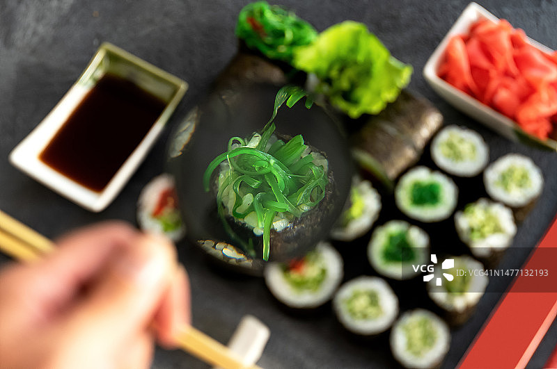 用放大镜观察寿司卷的成分，寿司卷特写，不同寿司卷的组合，灰色背景，顶视图图片素材