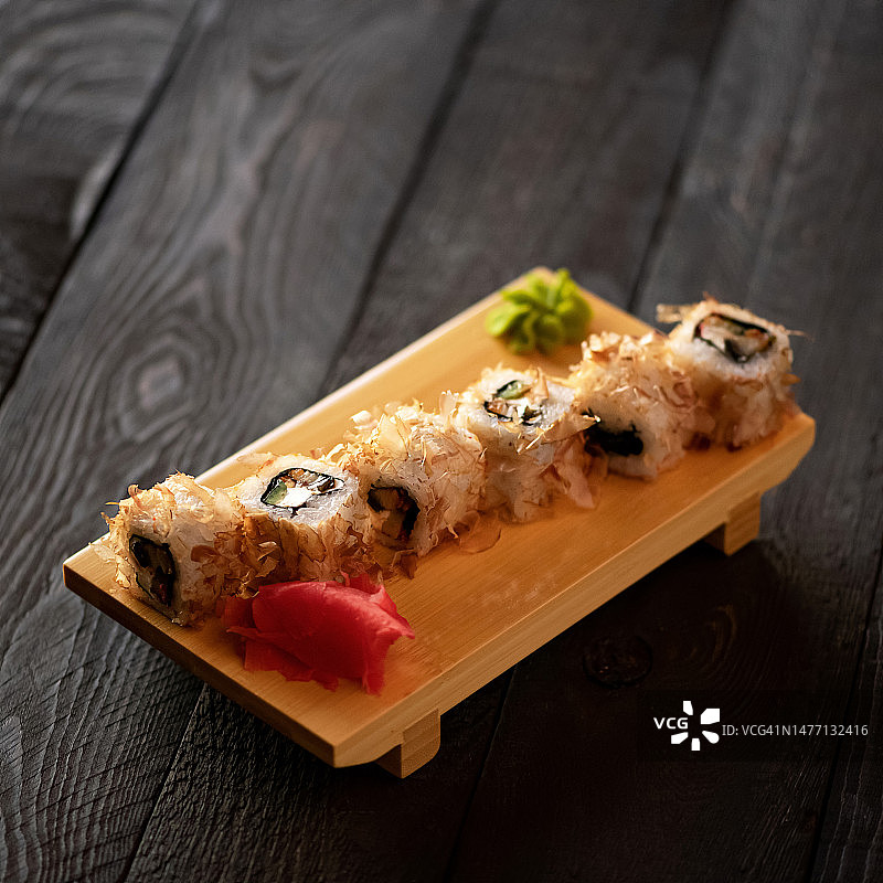 寿司卷组合：牛油果、三文鱼、奶油奶酪和鱼片，搭配芥末和姜，日式料理，深灰色木质背景图片素材