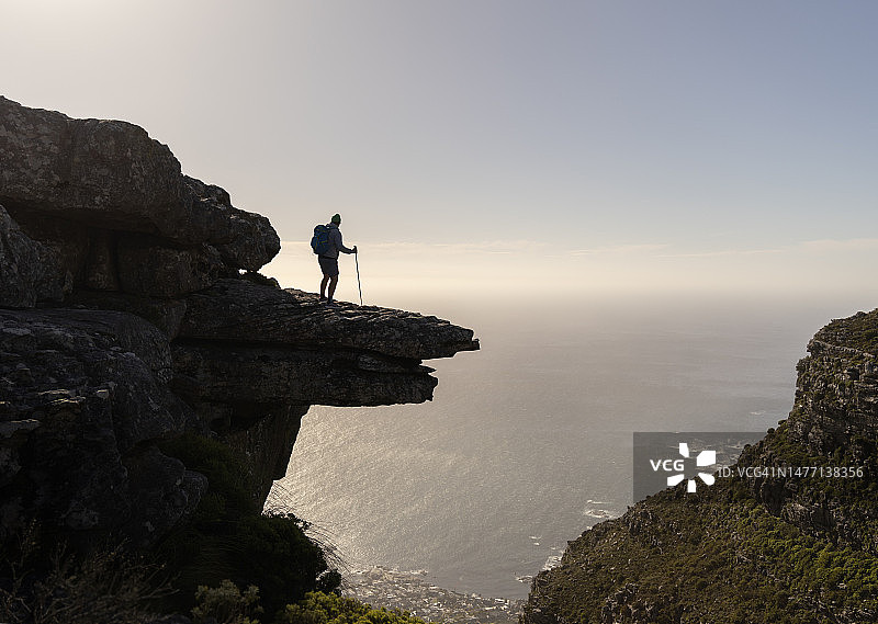 徒步者站在高出海面的悬挑山岩上图片素材