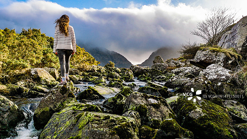 爱尔兰凯里郡邓洛峡谷鸟瞰图，女子站在河中石头上欣赏自然风光图片素材