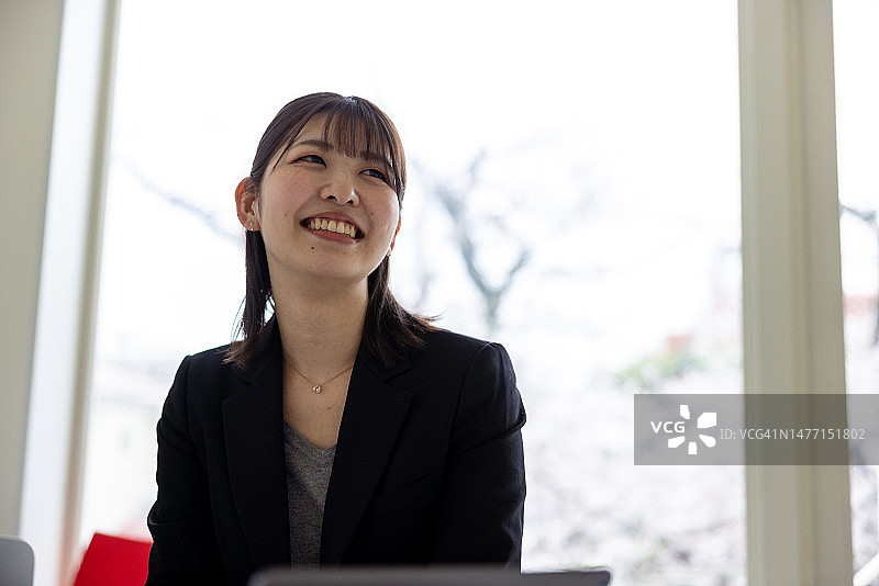 年轻女商人看着墙上的屏幕，与在家办公的同事讨论图片素材