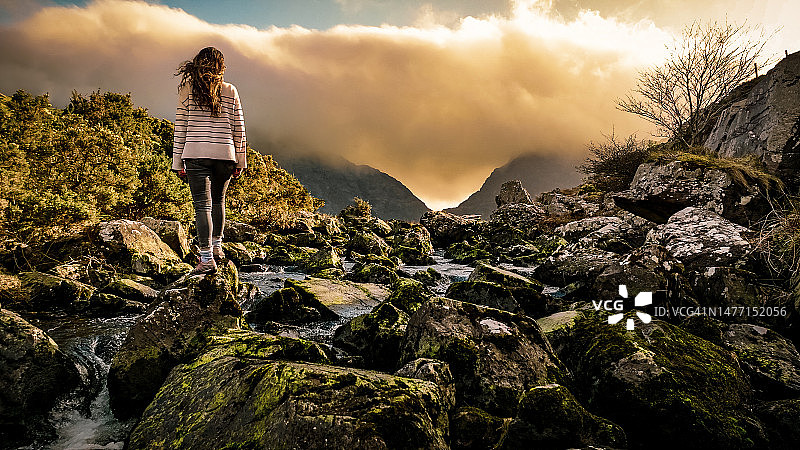 爱尔兰凯里郡邓洛峡谷鸟瞰图，女子站在河中石头上欣赏自然风光图片素材