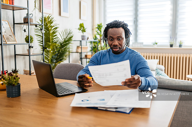 青年男子在家用笔记本电脑查看财务状况图片素材
