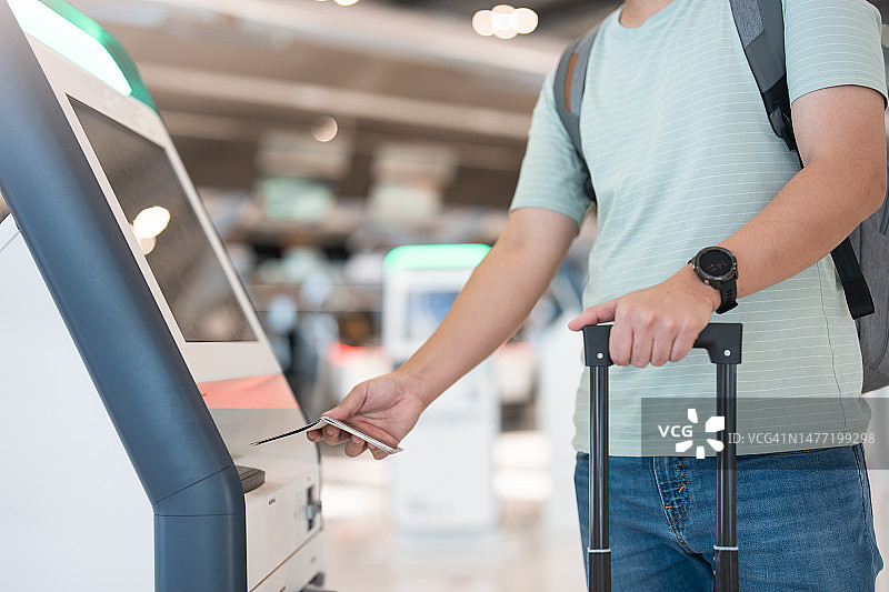 年轻的亚洲男人在机场使用自助值机终端图片素材
