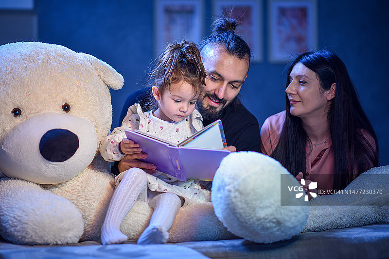 父母在睡前与孩子一起读书图片素材