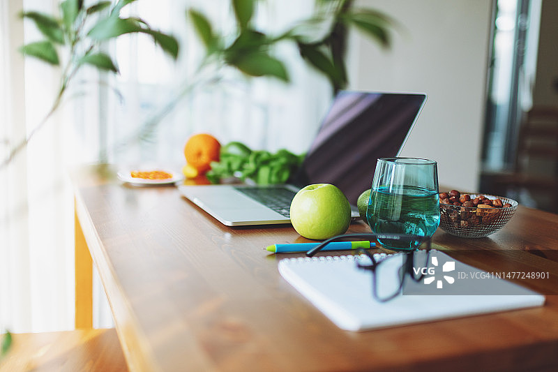营养师的工作场所，配有笔记本电脑、眼镜、水果、Omega-3胶囊、蔬菜、坚果和绿色蔬菜图片素材