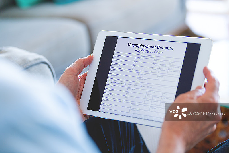 男子在平板电脑上看失业救济金申请表图片素材