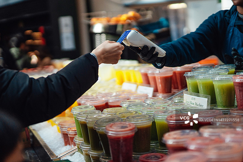 顾客在当地食品市场使用信用卡进行非接触式支付图片素材