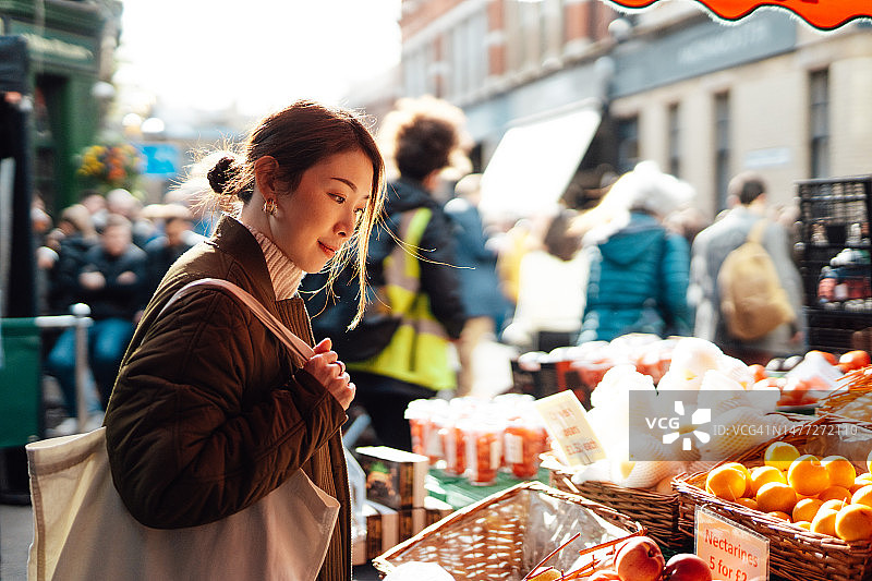 在当地农贸市场购买水果和蔬菜的年轻亚洲女性图片素材