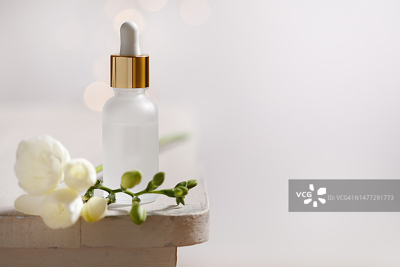 带有鲜花的白色和金色面部精华液瓶图片素材