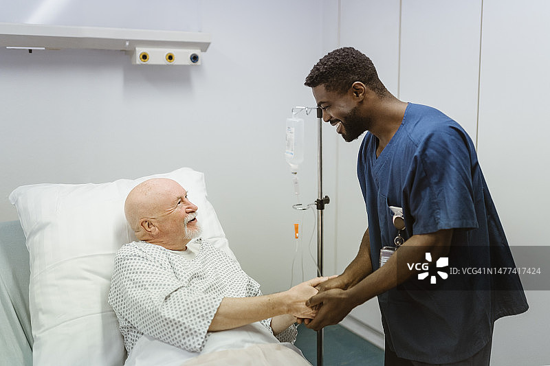 微笑的医护人员握着老年男病人的手图片素材