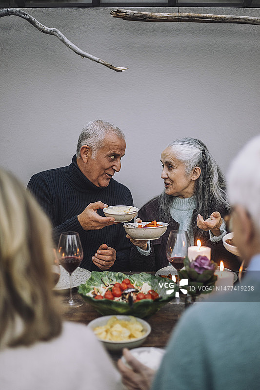 男女朋友在晚宴上手捧食物碗交谈图片素材