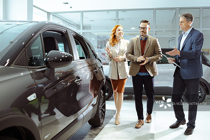 情侣购买新车并与销售人员交谈图片素材