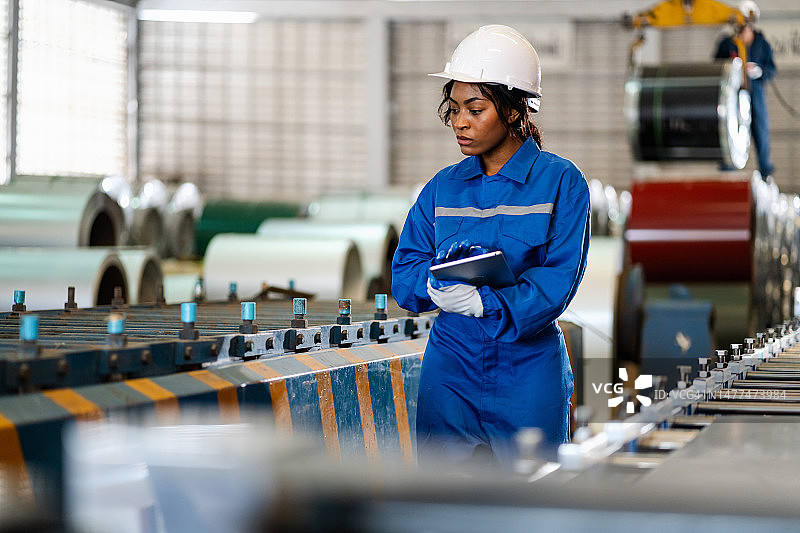 金属板材厂内检查机器的女工，工厂安全生产概念图片素材
