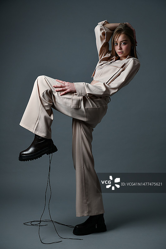 系鞋带的可爱女人在灰色背景上展现时尚自信图片素材