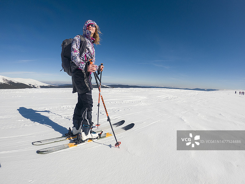 阳光明媚的日子里，年轻的白人妇女滑雪旅行。热爱冒险的女性图片素材