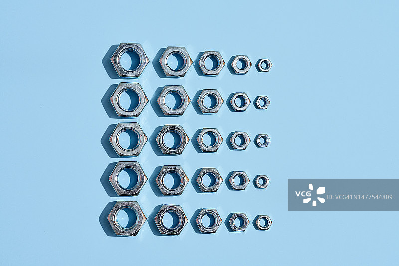 排列在蓝色背景上的多种不同尺寸的六角螺母图片素材