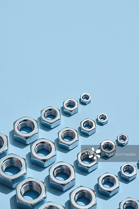 排列在蓝色背景上的多种不同尺寸的六角螺母图片素材