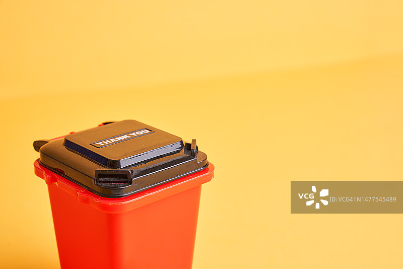黄色背景上的红色回收垃圾箱图片素材