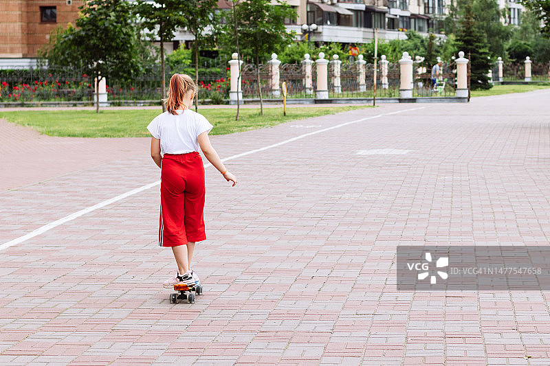 女孩在街道人行道上玩滑板图片素材