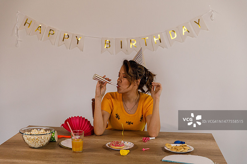快乐年轻女人独自庆生吹喇叭图片素材