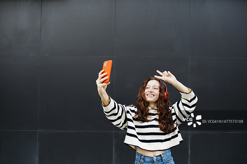 戴着耳机和手机跳舞的红发女人图片素材