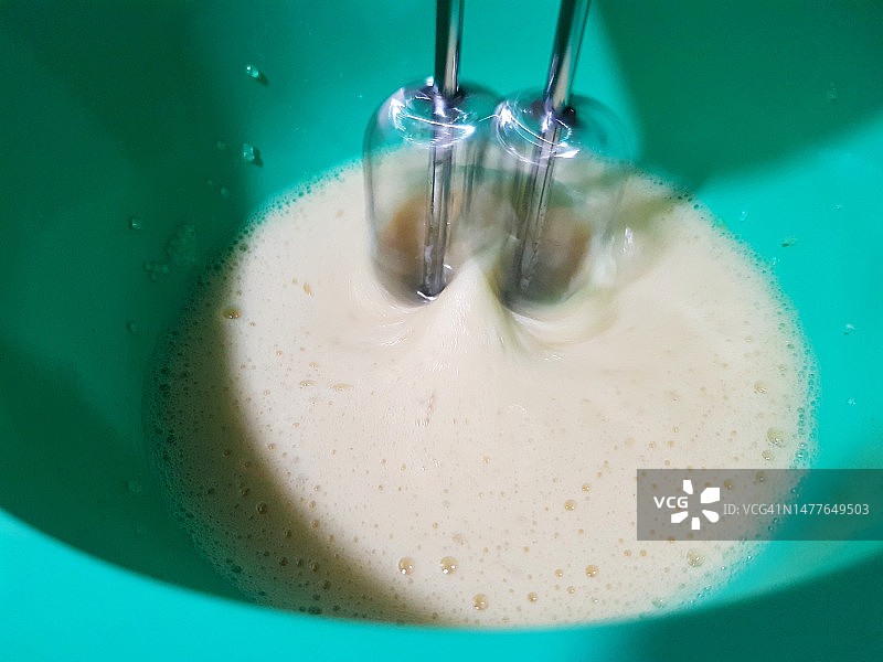在绿色碗中用电动手持搅拌器混合鸡蛋图片素材