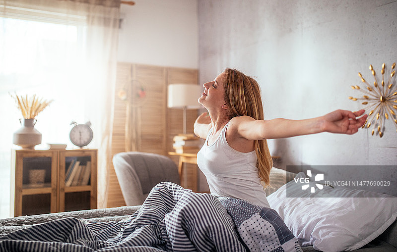 女人在床上放松，伸展双手图片素材