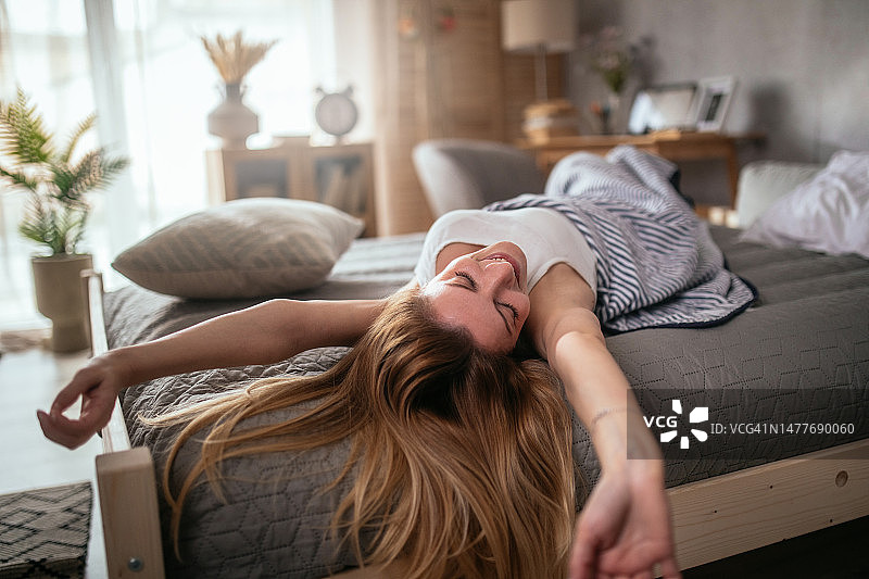 女人在床上放松，伸展双手图片素材