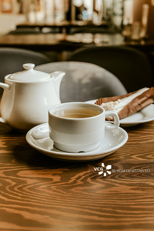 咖啡馆桌子上的一杯茶和一个奶油夹心饼图片素材