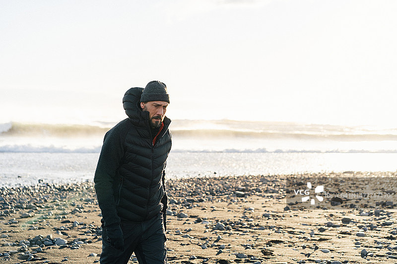 日落时分在冰岛黑色海滩上行走的男人们图片素材
