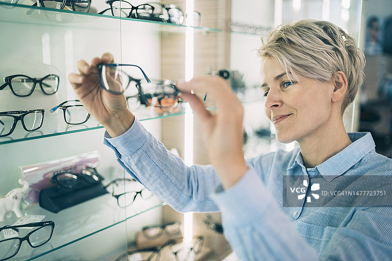微笑的年轻女子欣赏她的新眼镜图片素材