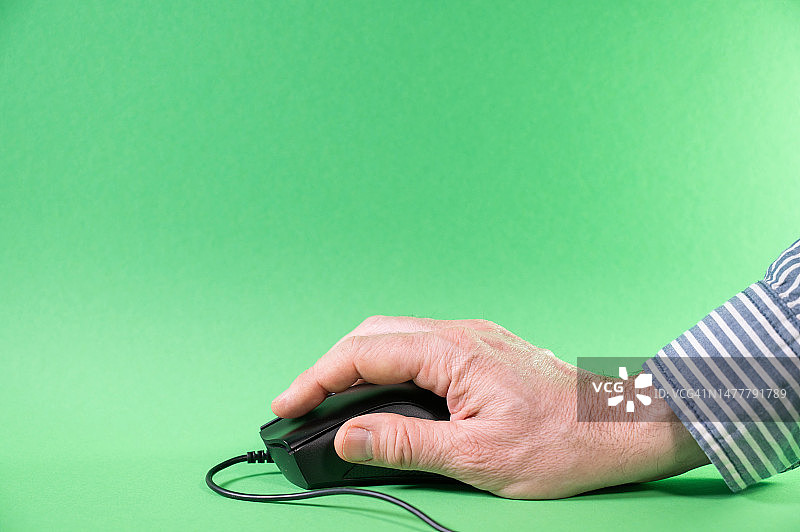 一个人使用电脑鼠标，绿色背景。图片素材
