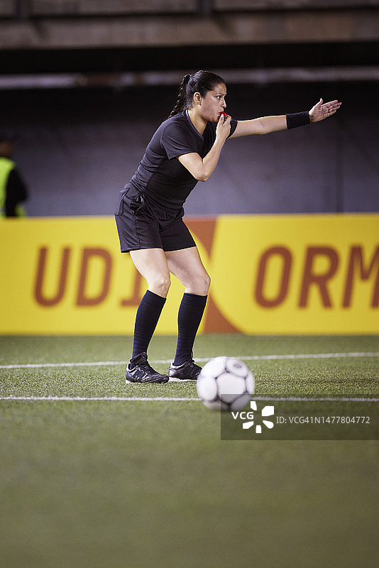 职业女足球裁判吹响哨子示意任意球图片素材