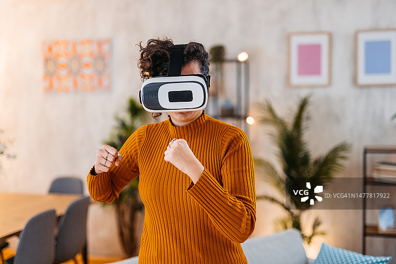 年轻女人在家戴着VR头显玩拳击游戏图片素材