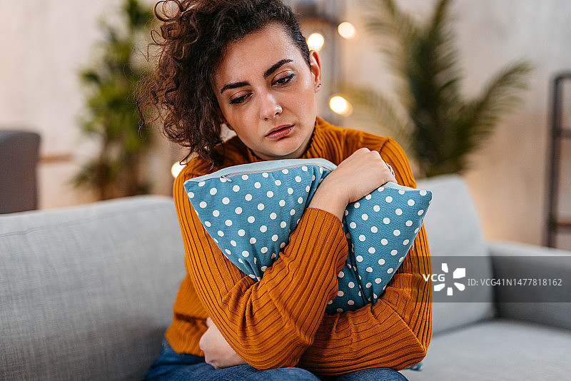 悲伤的年轻女人在家抱着枕头哭泣图片素材