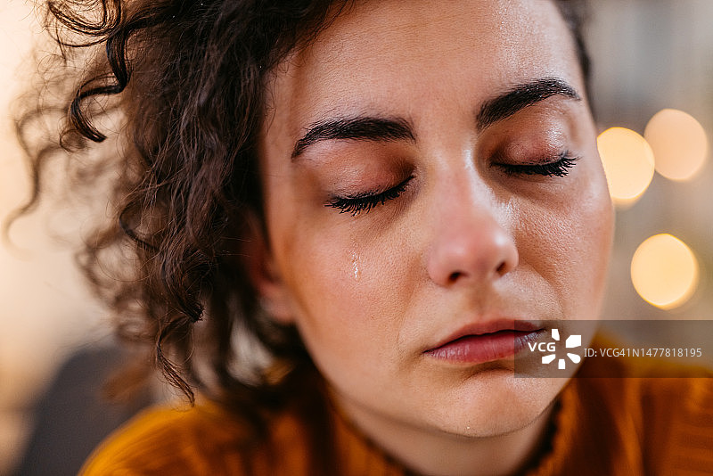 夜晚在家哭泣的悲伤的年轻女子图片素材